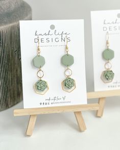 the earrings are on display in front of a white card and wooden stand with an earring