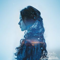 a woman with long hair standing in front of a blue sky and snow covered ground