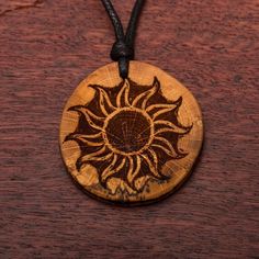 a wooden pendant with a sun design on it