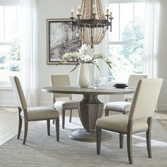 a dining room table with four chairs and a chandelier hanging from the ceiling