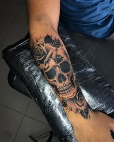 a man with a skull and roses tattoo on his arm