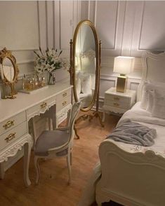 a bedroom with white furniture and gold accents on the walls, along with a large mirror