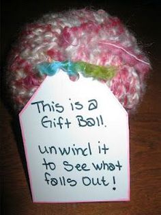 a pink and white crochet hat with a tag attached to it that says, this is a gift ball unwrrl it to see what falls out