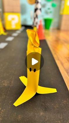 an origami banana sitting on the floor in front of a playroom with other toys