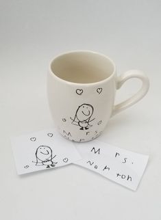 two coffee mugs sitting next to each other on top of a white tablecloth