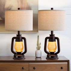 two lamps sitting on top of a wooden dresser