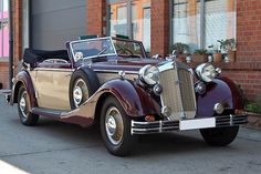 an antique car parked in front of a brick building