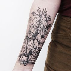 a woman's arm with flowers and leaves on the left side of her arm