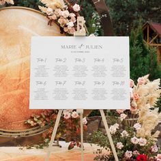 a wedding seating chart is displayed on a easel with flowers and greenery around it