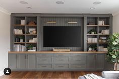 a living room with built in bookshelves and a flat screen tv on the wall