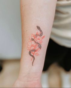 a woman's arm with a snake and flowers tattoo on the left side of her wrist