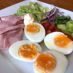 an assortment of food on a plate including hard boiled eggs, ham, lettuce and tomatoes