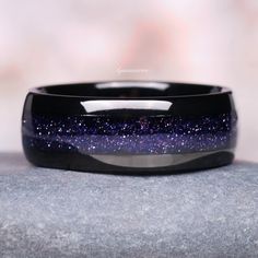 a black band with blue and white speckles on it sitting on top of a rock