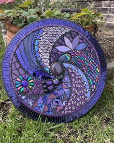 a purple plate sitting in the grass next to a potted plant