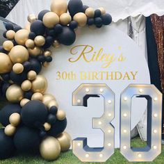 an image of a 30th birthday celebration with balloons and lights on the grass in front of a sign