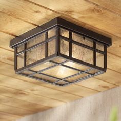 a square light fixture hanging from the ceiling in a room with wood paneled walls