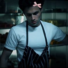 a man wearing an apron and bow tie standing in front of a refrigerator with his hands on his hips