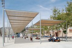 people are sitting on benches under an awning