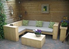 a wooden bench sitting next to a white couch on top of a brick floor covered patio