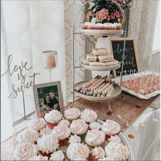 cupcakes and pastries displayed on a table in front of a wedding photo