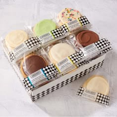 six decorated cookies in a box on a table with checkered ribbon around the edges