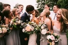 a group of people standing next to each other with flowers in their hands and laughing