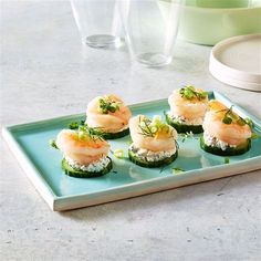 small appetizers are arranged on a blue plate with green garnishes