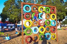 a child is playing on an outdoor play structure made out of plastic rings and tires