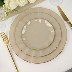 there is a table setting with plates and silverware on it, along with flowers