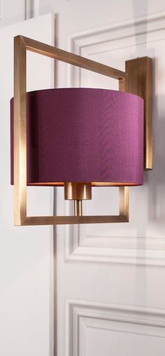 a purple lamp hanging from the side of a wall next to a white door with a gold frame