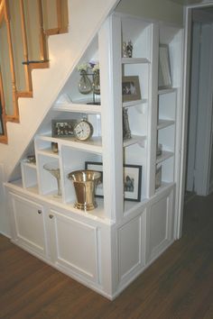 an open bookcase under the stairs in a house