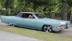 an old car is parked on the side of the road in front of some trees