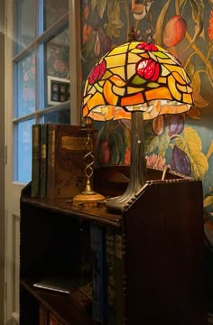 a lamp sitting on top of a wooden table next to a book shelf and window