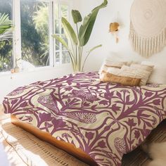 a bed in a bedroom with a purple and white comforter on top of it