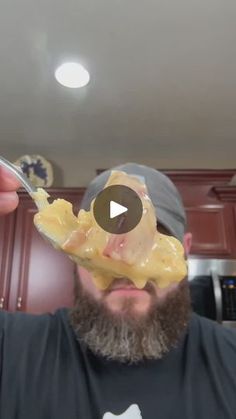 a man with a beard is holding up a doughnut to his face and looking at the camera