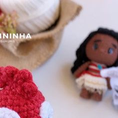 two crocheted dolls sitting next to each other on top of a white table