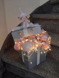 a gift box with ornaments and lights on the top is sitting on some stairs next to a stair case