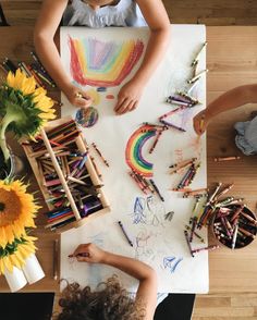 two children sitting at a table with crayons and colored pencils on it