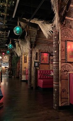 the interior of a tropical themed restaurant with red booths and palm trees hanging from the ceiling