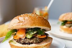 two hamburgers with lettuce, carrots and other toppings on a white plate