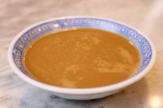 a blue and white bowl filled with soup on top of a table