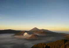 an aerial view of the top of a mountain with low lying clouds in the foreground