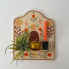 an air plant sitting on top of a wooden shelf next to a candle and vase