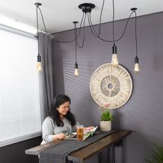 a woman sitting at a table with food and drinks in front of her, surrounded by hanging lights