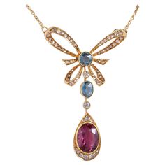 This enchanting Edwardian period necklace is 1910 ca Exquisite and feminine bow design with suspended drop all set with rare gemstones, untreated and unheated, skillfully rendered of solid 18 Kt gold Set with a beautiful 4.00 carat natural Tourmaline Red Pink intense color also denominated as Rubellite – natural untreated -measuring 12.11 mm. x 9.01 mm. – making the focal point of the centre piece Sky Blue color Natural Tourmaline for 1.35 Ct and 1.40 Ct of rose cut diamonds of fine quality supp Edwardian Pendant, Blue Gem Necklace, Red Pendant Necklace, Rare Jewelry, Vintage Pendant Necklace, Necklaces Pendant, Red Pendants, Bow Necklace, Tourmaline Jewelry