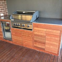 an outdoor bbq with grill and counter top on wooden flooring next to brick wall