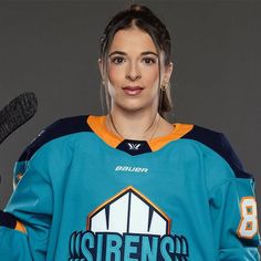 a female hockey player is posing for the camera with her gloves in front of her