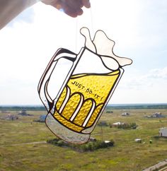 a person holding up a beer mug stained glass ornament in the shape of a mug