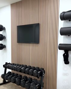 there is a gym room with black dumbs and a flat screen tv on the wall