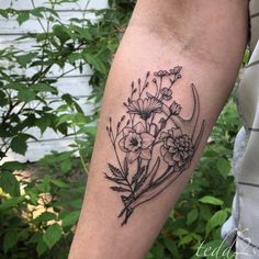 a black and white flower tattoo on the left arm, with flowers in it's center